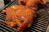 beer-brined whole chicken seasoned with roasted garlic on a grill