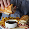 Dipping sandwich into Fire & Smoke Society Big Dipper Au Jus