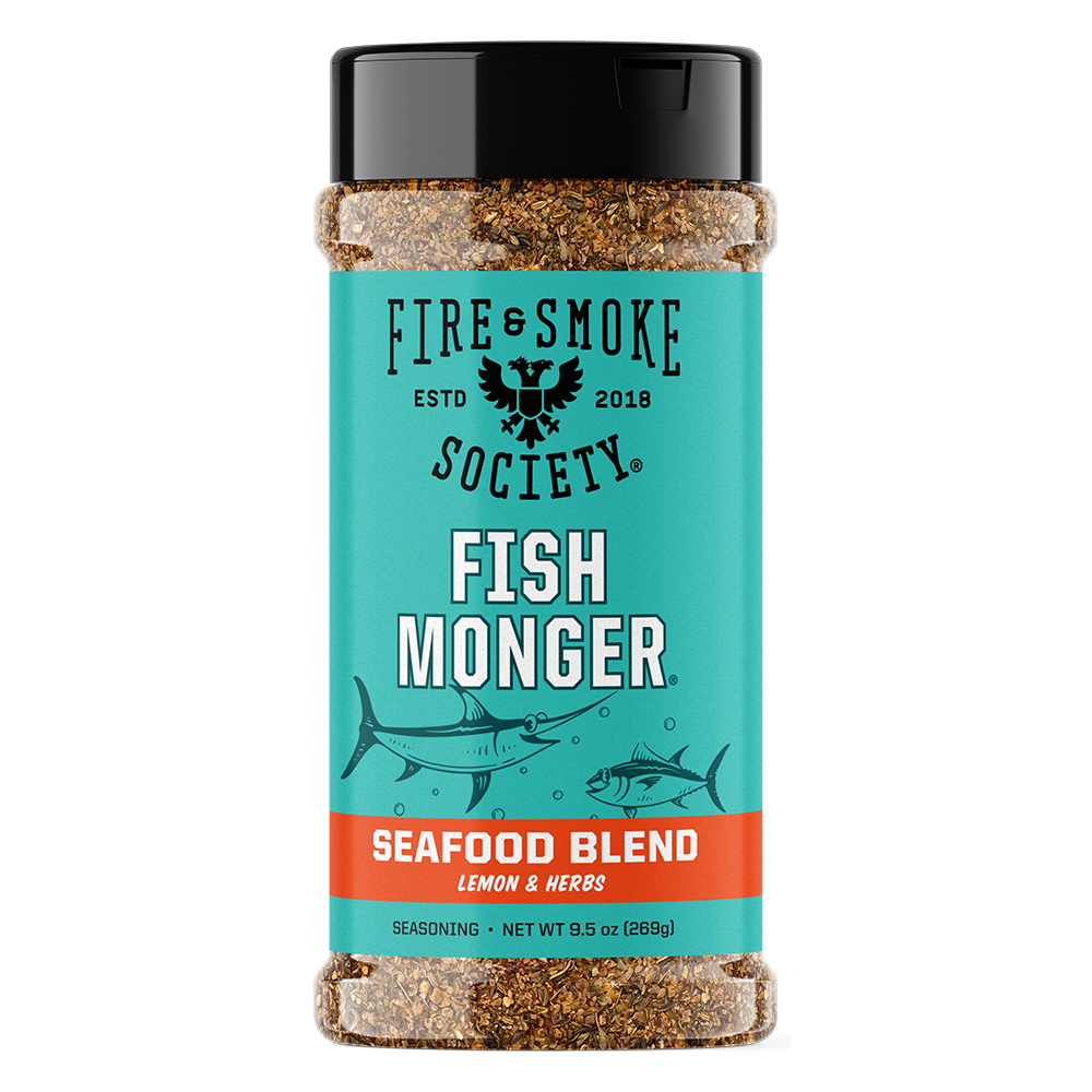 A bottle of Fire & Smoke Society Fish Monger Seafood Blend seasoning, featuring a turquoise label with black and white text, a red band, and illustrations of fish, topped with a black cap.