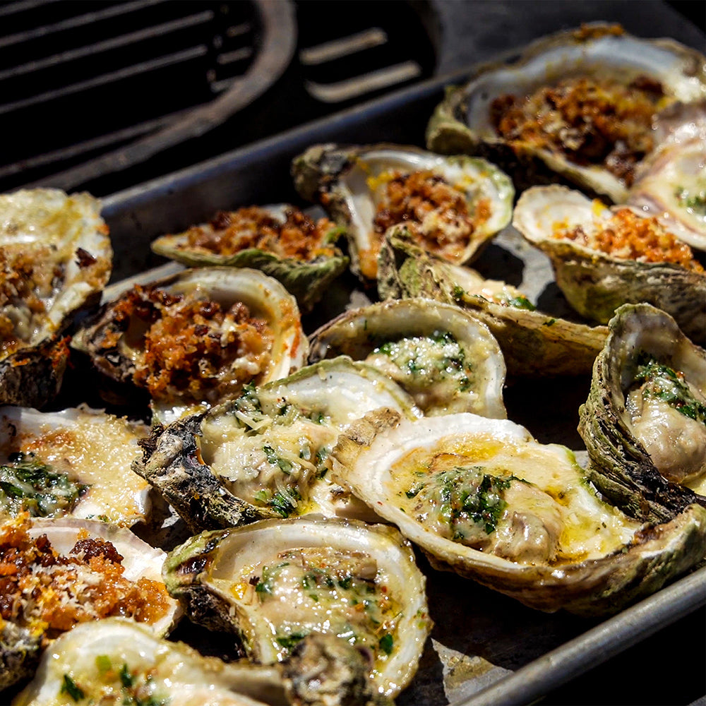 Grilled oysters on a grill pan with herbs and spices.