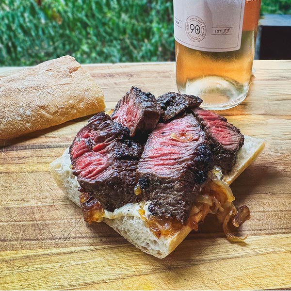 steak sandwich next to bottle of wine
