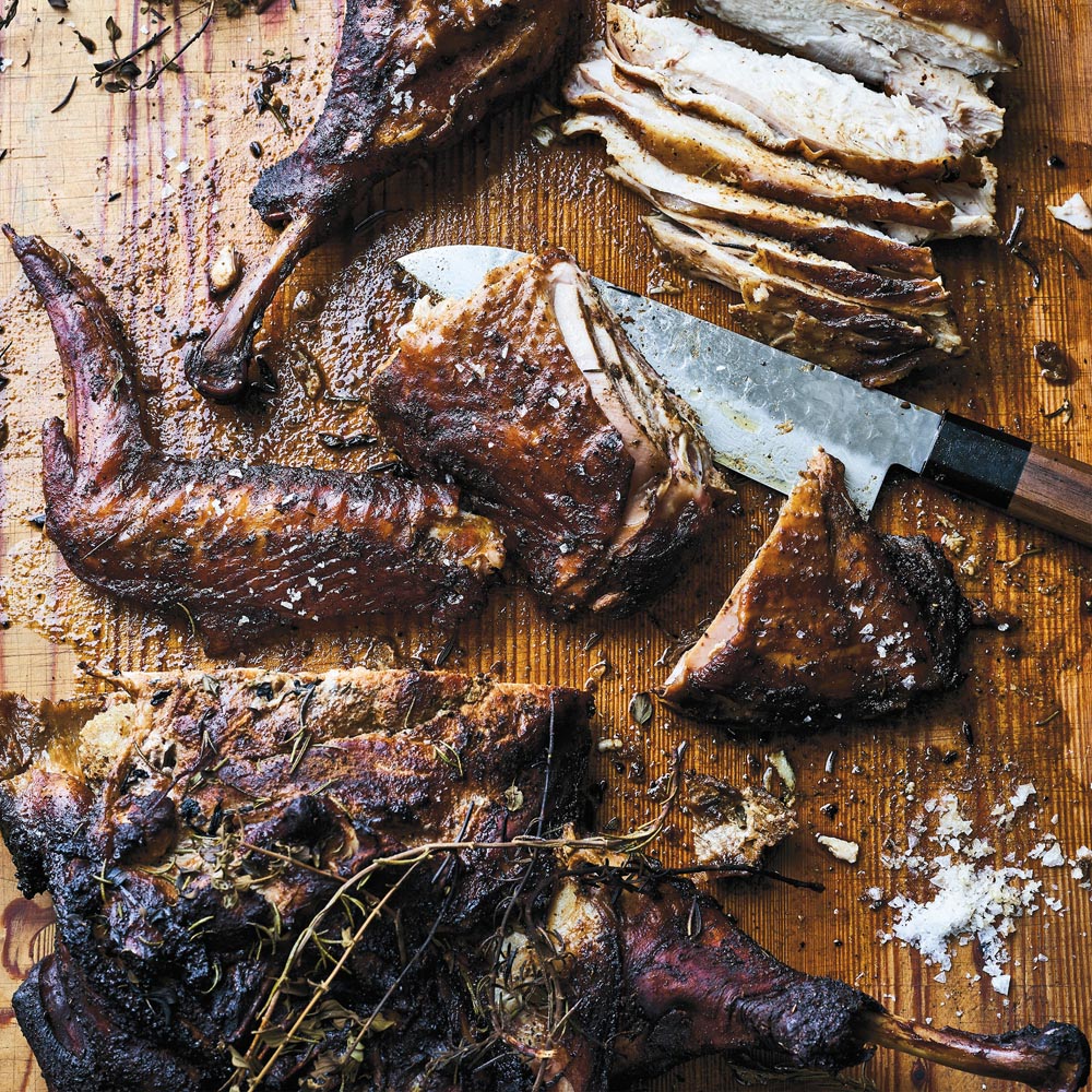 Roasted chicken pieces on a wooden cutting board with a knife