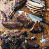 Roasted chicken pieces on a wooden cutting board with a knife