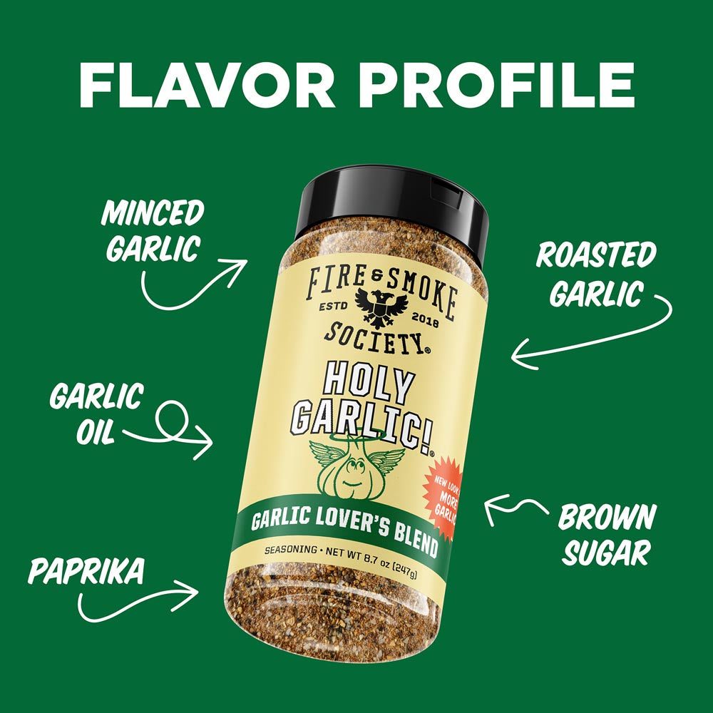 A bottle of Fire Smoke Society Holy Garlic! seasoning centered on a dark green background with white text and arrows labeling flavor ingredients: minced garlic, roasted garlic, garlic oil, paprika, and brown sugar.