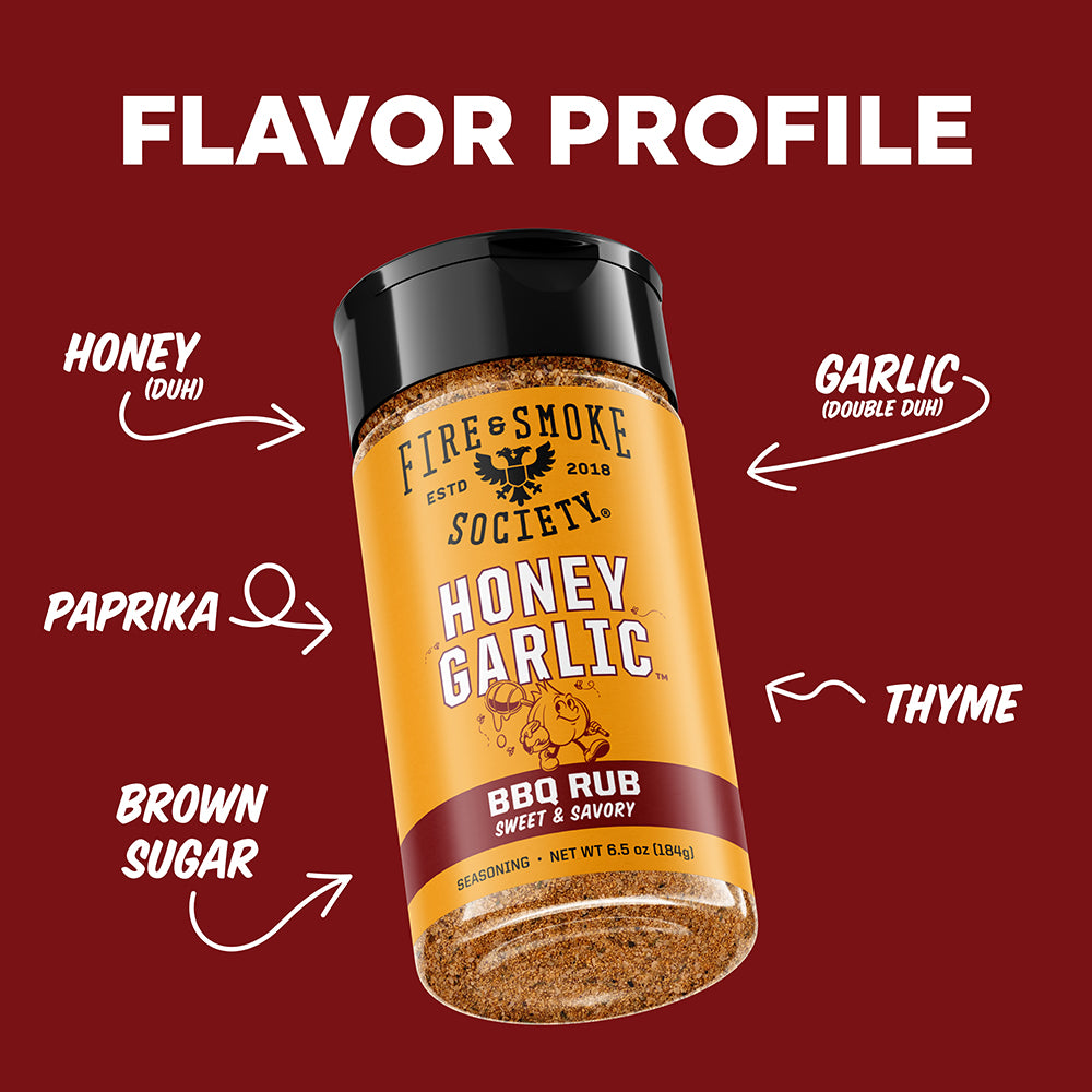A bottle of Fire & Smoke Society Honey Garlic BBQ Rub seasoning is centered on a dark red background with white text and arrows labeling the flavor profile as Honey, Garlic, Paprika, Brown Sugar, and Thyme.