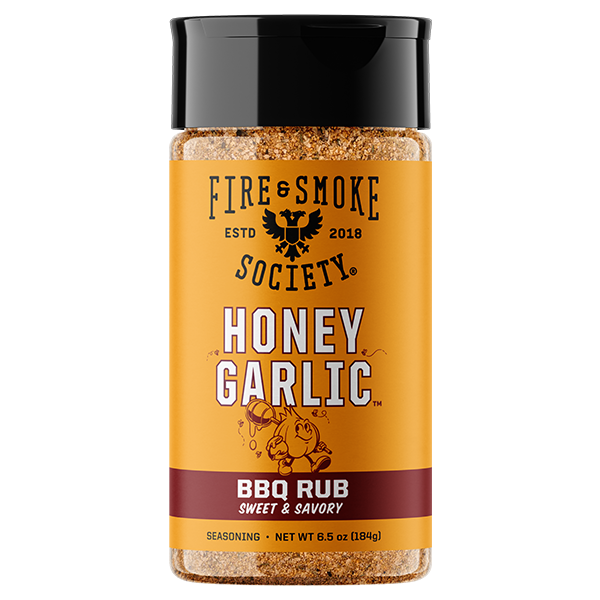A bottle of Fire & Smoke Society Honey Garlic BBQ Rub seasoning, featuring a bright yellow-orange label with black and white text, a black cap, and visible brown seasoning inside, set against a plain white background.