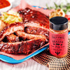 Sliced ribs on a platter with a jar of 'Salt-Free Flavor Brazen Pig' BBQ blend next to it.