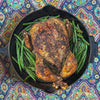 Roasted chicken with green beans in a cast iron skillet on a colorful patterned surface
