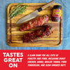 Wooden cutting board with meat, a knife, rosemary, and a jar of Coop de Thrill seasoning on a blue denim background.