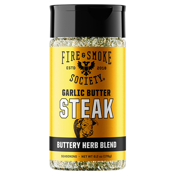 A bottle of Fire & Smoke Society Garlic Butter Steak seasoning, featuring a bright yellow label with a black cap and black text, on a solid white background.