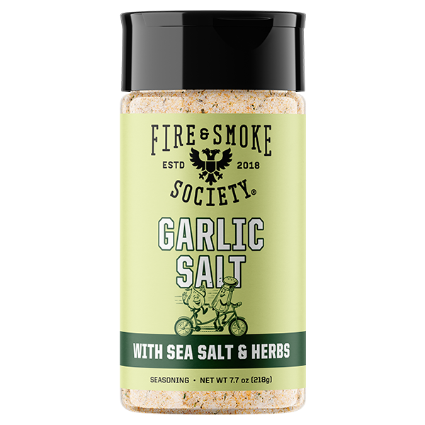 A bottle of Fire & Smoke Society Garlic Salt seasoning with sea salt and herbs, featuring a light green label and a black cap, shown on a white background.