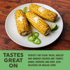 Three ears of corn on the cob with butter and lime slices on a white plate, served on a wooden table.