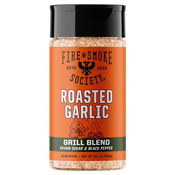 A bottle of Fire & Smoke Society Roasted Garlic Grill Blend seasoning, featuring an orange label with a black cap and showing the seasoning granules through the clear plastic bottle.