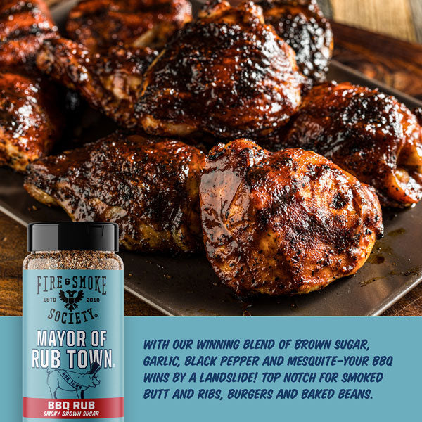 Grilled chicken pieces on a tray with a bottle of 'Mayor of Rub Town' BBQ rub from Fire & Smoke Society.