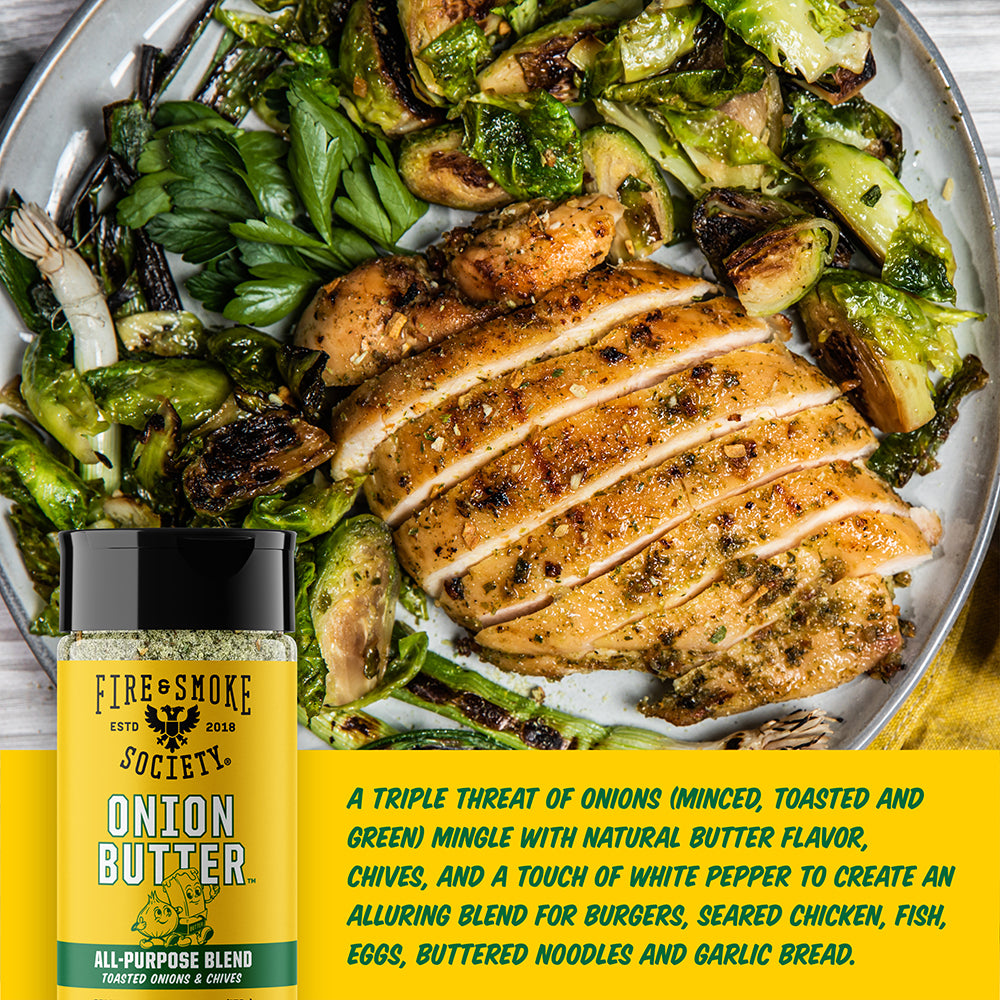 A bottle of Fire & Smoke Society Onion Butter seasoning is shown in front of a plated meal of grilled chicken and roasted Brussels sprouts. A yellow text banner at the bottom describes the flavor profile and ingredients.