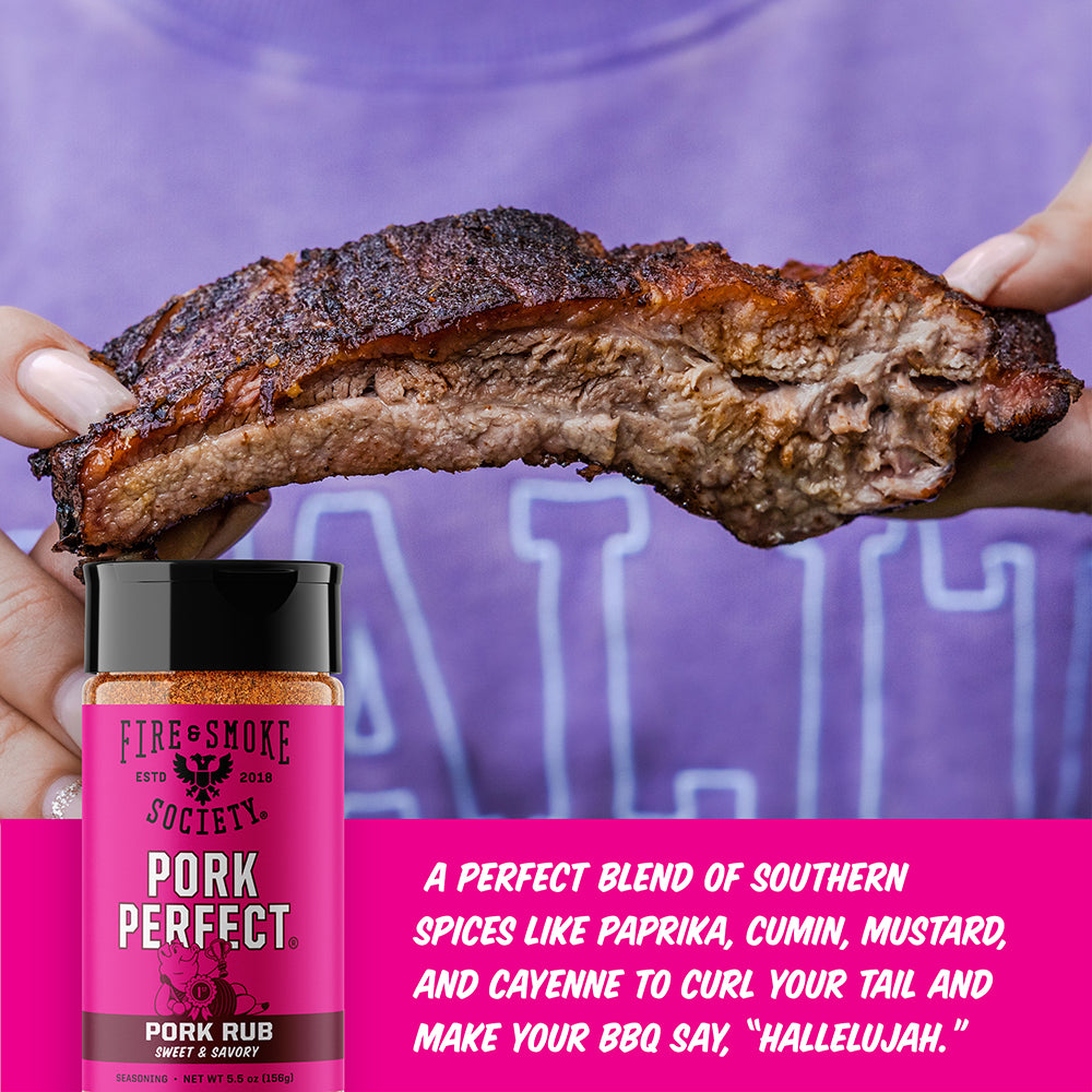 A jar of Fire & Smoke Society Pork Perfect rub sauce is shown in front of a person holding a large, cooked pork rib. A bright pink text banner on the right lists the spice blend ingredients.