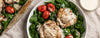 Bowl of salad with chicken and tomatoes on a textured surface