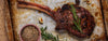 Grilled steak with rosemary on a rustic metal tray