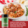 Spaghetti with meatballs and a bottle of Italian seasoning on a checkered tablecloth.