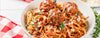 Spaghetti with meatballs on a white plate with a red and white checkered cloth.