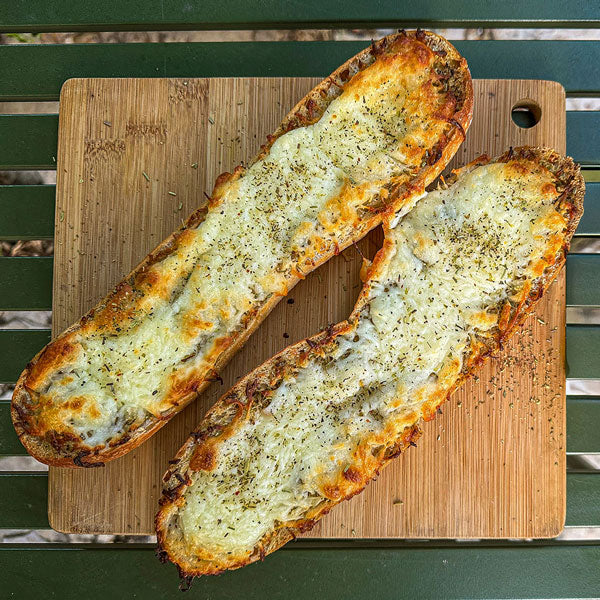 Two slices of garlic bread with cheese on a wooden cutting board.